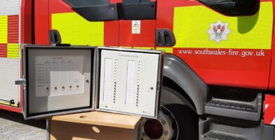 The BS 8629 compliant EvacGo panel is shown with its door open, in front of a fire engine